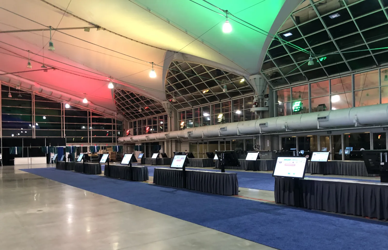 Registration kiosks on stands along draped tables in a convention center hall