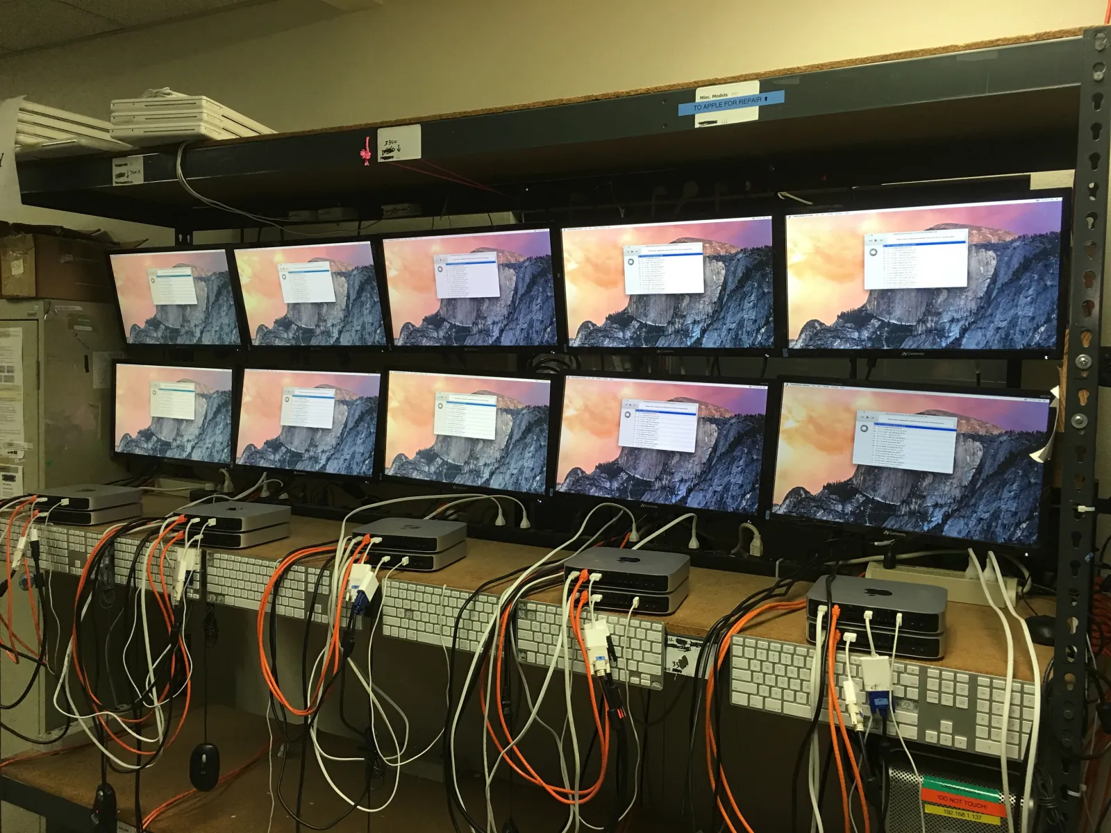 The imaging bench: two rows of monitors above Mac minis, each cabled to the network while it is set up