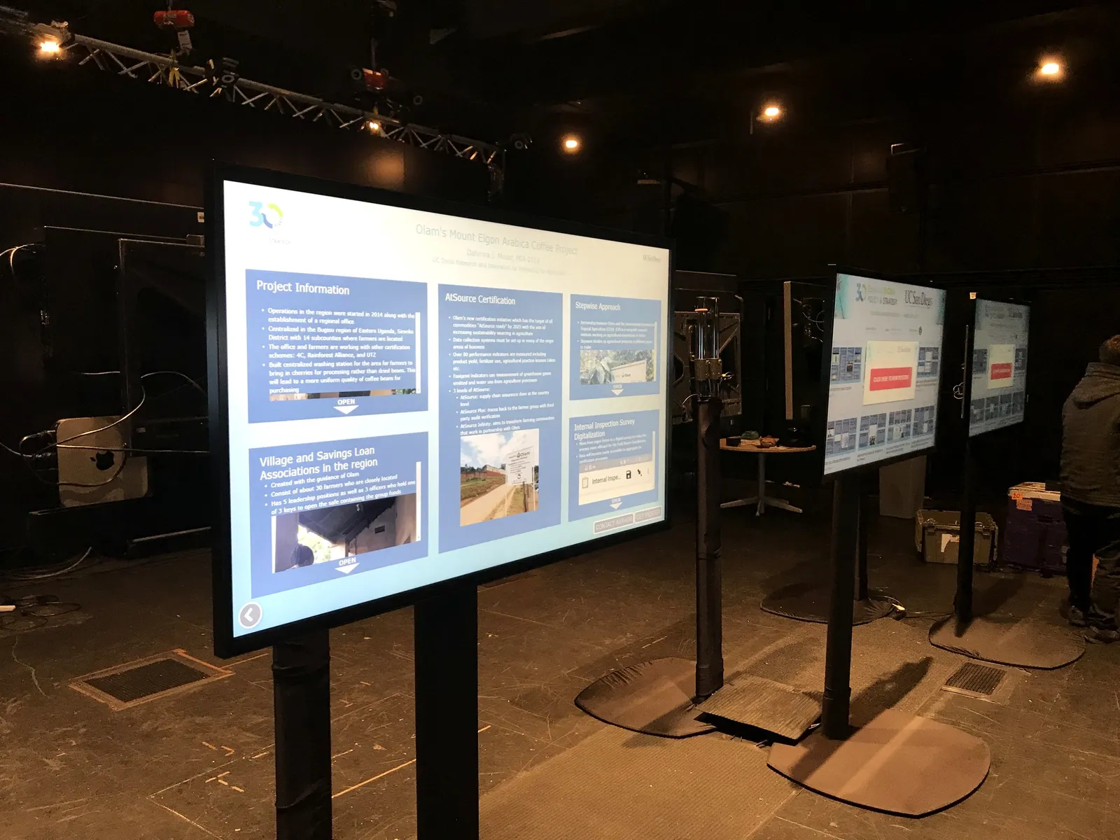 Large displays on floor stands in a darkened hall